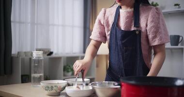 Handheld selective focus shot,Beautiful woman is preparing the process of coating chicken with all the ingredients in a bowl before frying the chicken on a pan. Cooking concept, Food preparation video