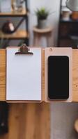 A smartphone and a clipboard on a wooden table photo