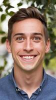 A man smiles for the camera while standing in front of trees photo