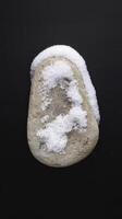 A rock covered in snow on a black background photo