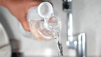 Pouring water from a container into a glass at a kitchen sink video