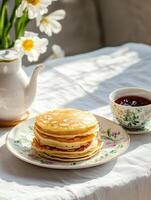 Stack of homemade pancakes with tea and jam, set in a bright breakfast scene. Morning treat photo
