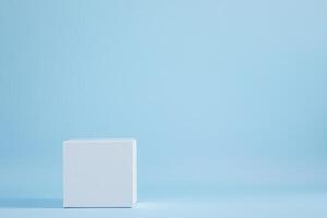 Minimalist cube display platform against a soft blue background. Clean geometric presentation photo