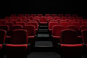 Rows of empty red seating in a dark movie theater or auditorium, awaiting an audience photo