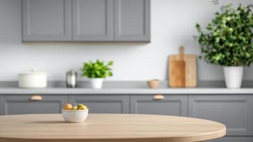 A serene kitchen scene features a bowl of fruit on a wooden table in front of grey cabinets photo
