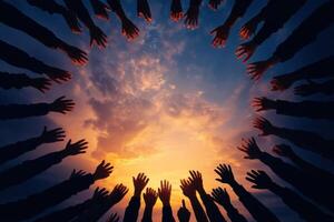 Silhouetted arms and hands reach towards a vibrant, colorful sunset, conveying unity and hope photo
