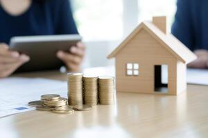 Financial planning for homeownership, stacks of coins and a miniature wooden house on a desk photo