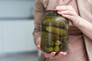 Jar of cucumbers in hand on a white background. Isolation photo