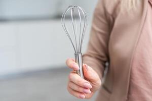 Female holding in hand whisk isolated on white background. Clipping Path. Full depth of field. photo