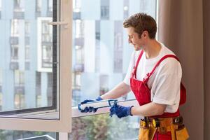 Worker installing plastic window indoors, closeup view photo