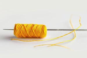 Bright Yellow Thread Spool and Needle Isolated on White Background photo