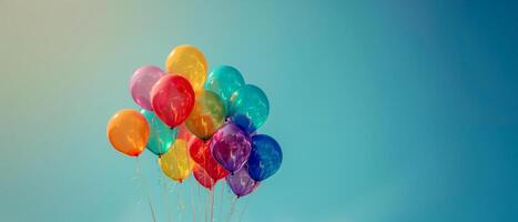 Floating rainbow color balloons on clear blue sky background, pride month celebration concept photo
