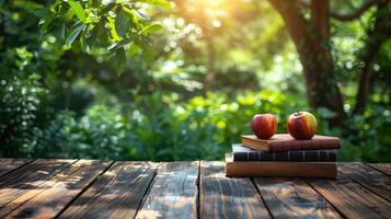 wooden table top with pile of books and apples on fresh morning garden background and warm sunlight photo