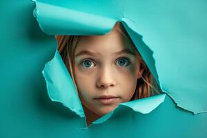 Little Girl Peeking Through Hole in Blue Paper photo