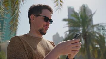 retrato do gadget viciado homem com Smartphone em cidade rua dentro verão, alegre cara lendo mensagem video