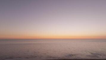 Horizon over the ocean showcases a stunning transformation of colors during sunset, creating a serene and peaceful atmosphere video