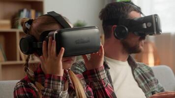 Modern Caucasian family little kid parent man wearing VR headset virtual reality glasses at home child girl guy father play 3D digital game male dad daughter enjoy metaverse innovative AR cyber tech video