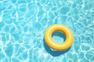 A bright yellow pool float rests in clear blue water. photo