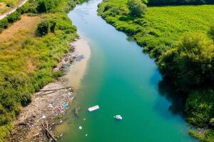 Aerial view of a river with visible pollution and surrounding greenery. photo