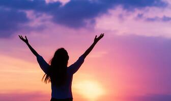 A woman with her arms up in the air at sunset photo