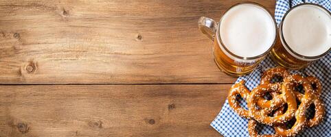 Two mugs of beer with pretzels on a wooden table setting. photo