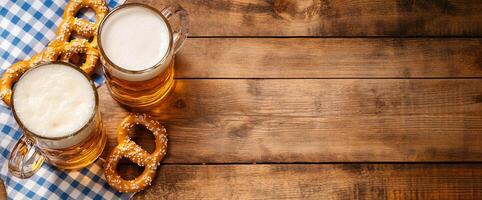 Two mugs of beer with pretzels on a checkered cloth over wooden table. photo