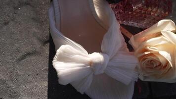 White Shoe with Large Bow, Cream Rose, and Pink Faceted Glass Object on Dark Background video