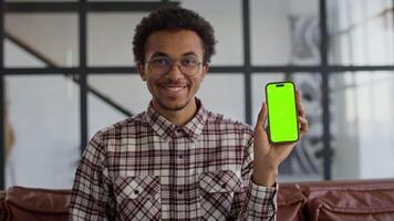Smiling man showing smartphone with green screen video