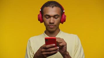 Man listening to music and browsing phone on yellow background video