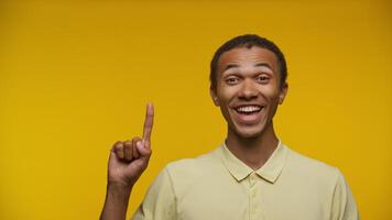 Smiling Man Pointing Upward on Yellow Background video