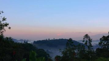 Time-lapse of the hills at the other side of the sunrise, with some mist, and a clear blue sky in the eastern Andean mountains of central Colombia. video