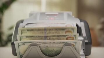 Money counting machine processing stacks of hundred-dollar bills video
