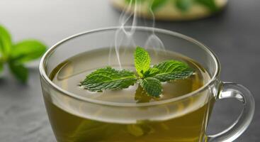 A close up of a cup of green tea with fresh mint leaves floating on top, representing health and vitality. photo