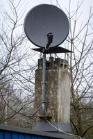 Satellite dish mounted on concrete chimney photo