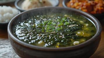 A steaming bowl of traditional Korean seaweed soup, with a side of rice and kimchi. 8 photo