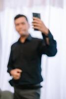 Blurred man capturing a selfie with smartphone in a bright ambient setting photo
