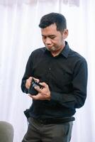 Man thoughtfully examines an empty wallet against a neutral backdrop photo
