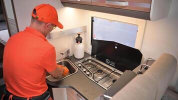 Man cleans RV camper van countertop and kitchen area in a mobile camper during sunny afternoon video