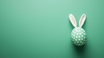 Green polka-dot egg with bunny ears on a green background. 11 photo