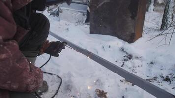 A highly skilled and experienced welder performs intricate metalwork with precision in challenging snowy conditions video