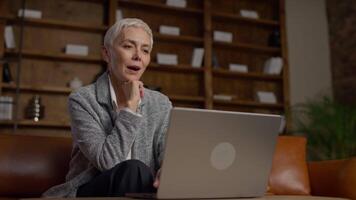Thoughtful Senior Woman Smiling While Using Laptop video