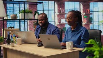 African american man and woman working remotely in their apartment, planning business strategies and discussing project development while using a laptop to track progress. Camera A. video