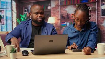 Worried African American woman looks at tax numbers on documents while her partner reassures her, helping with financial planning. Discussing ways to reduce expenses, save money. Camera A. video