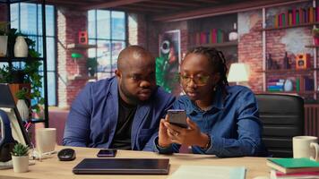 African american man and woman solving freelance tasks at home, working together on their phones to finish an important project for their employer. Networking with partners. Camera A. video
