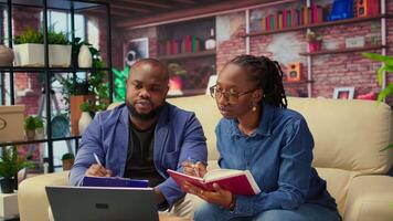 Mature people overseeing schedule and planning activities at coffee table, working on time management with online tools. Couple utilizing a notebooks and taking handwritten notes. Camera A. video