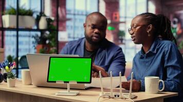 African American couple browse troubleshooting guide next to chroma key, working together to debug router issues and restore their home network. Freelancers getting angry. Camera B. video