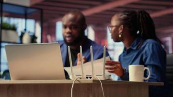 Black irritated man and woman rebooting their wireless router and checking network settings, feeling angry with the struggles to resolve an internet outage disrupting their tasks. Camera B. video