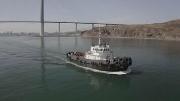 Aerial view of the tugboat in motion against the background of the bridge video
