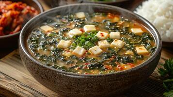 A steaming bowl of traditional Korean seaweed soup, with a side of rice and kimchi. 9 photo