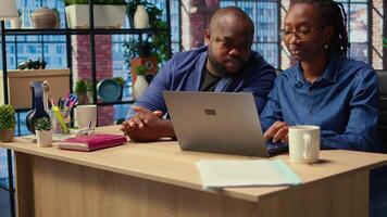 African american life partners working remotely in their cozy loft, planning development strategies and discussing project ideas while using a laptop to track progress. Cooperation. Camera A. video